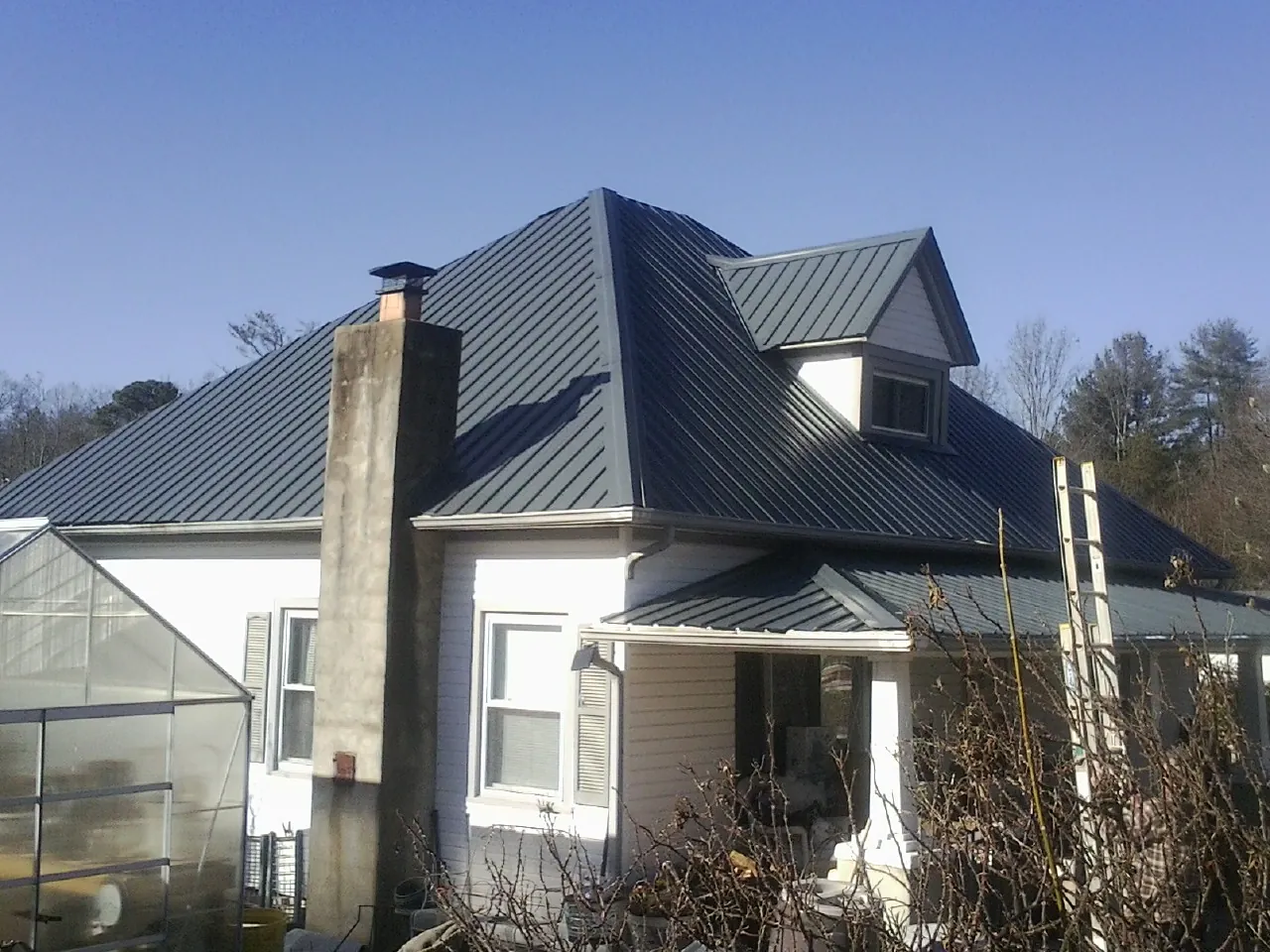 Dark blue standing seam metal roof on a white farmhouse with dormer — Slate & Tile Roof Repair by Roofing Brothers in Sidney Center
