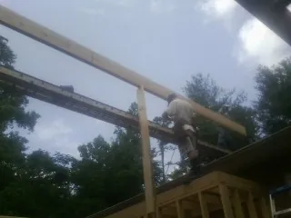 Carpenter setting a ridge beam over a new addition frame — Ice Dam Removal by Roofing Brothers in Sidney Center