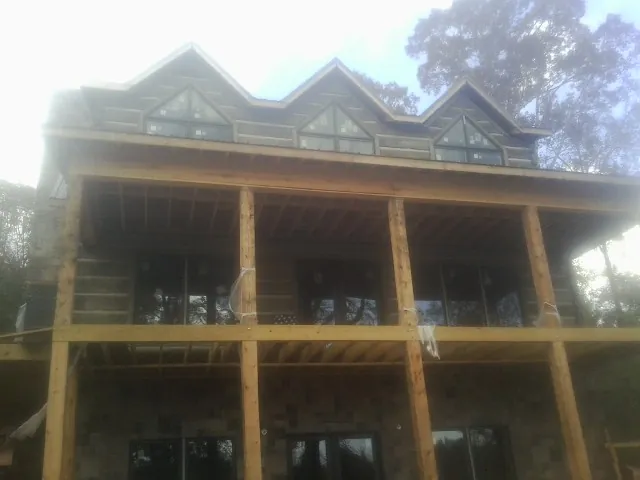 Dormers and porch framing on a large log home under construction — Roof Coating work by our crew in Sidney Center