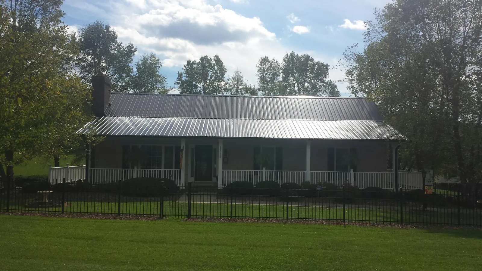 Gray metal roof on a brick ranch with a full width front porch — Gutter Guard Installation work by our crew in Sidney Center