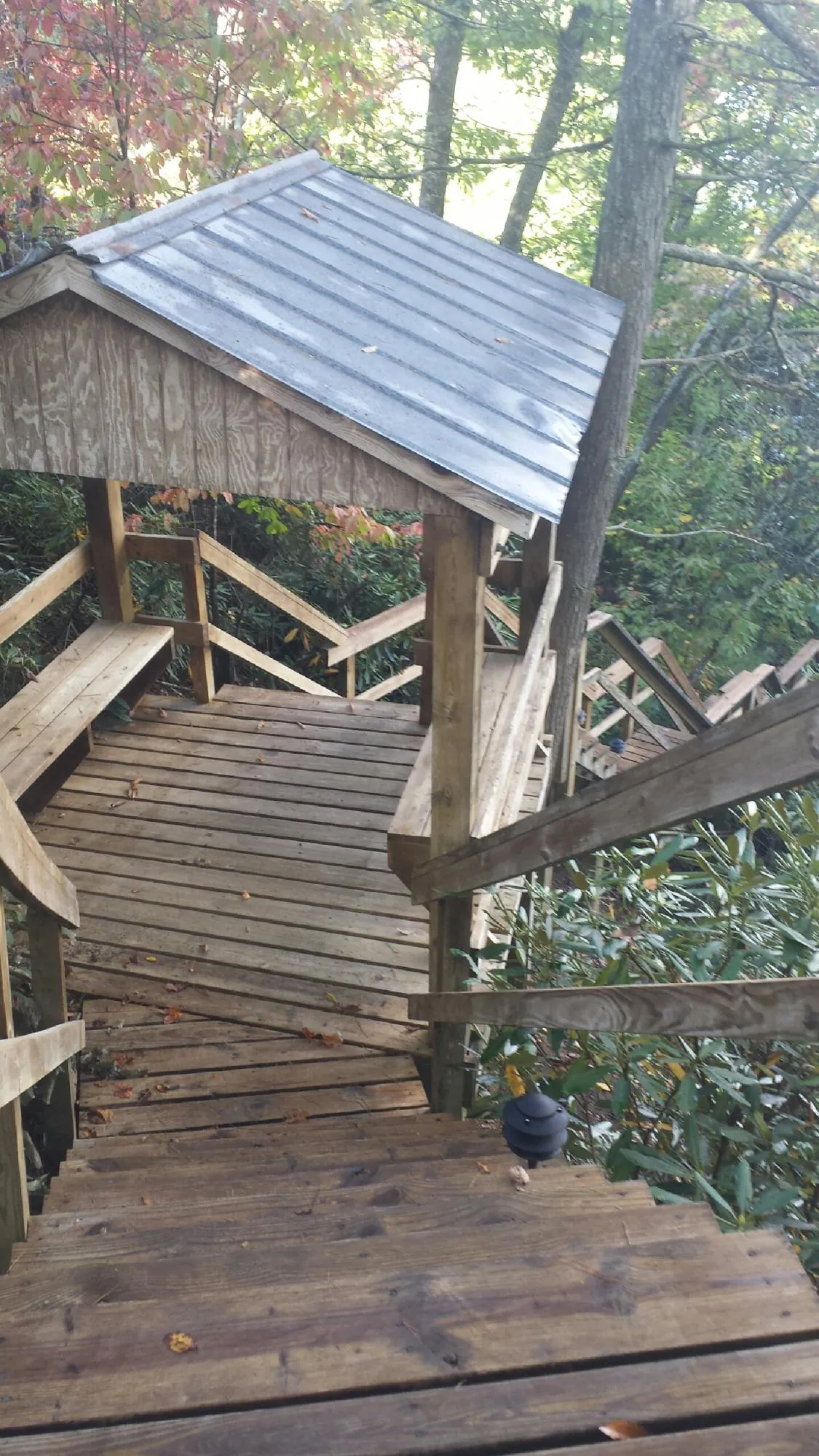 Metal roofed shelter over wooden steps on a wooded walkway — Skylight Repair & Installation work by our crew in Sidney Center