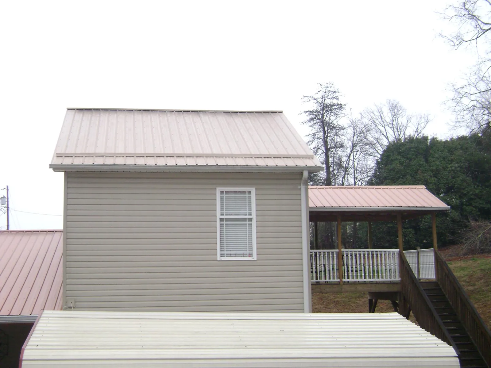 Tan metal roofs on a two story addition and attached porch, from a Roof Replacement job in Sidney Center